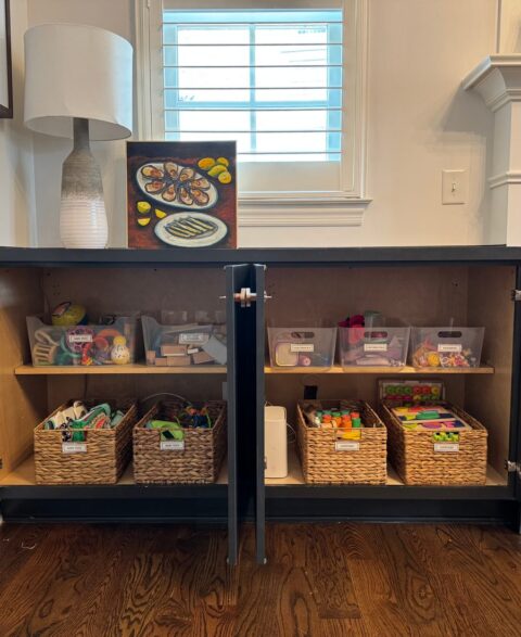 Living room cabinet after organizing with labelled baskets